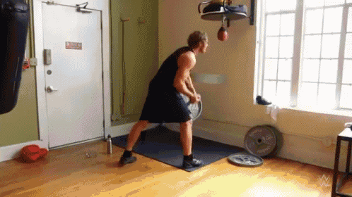 a man is standing on a mat in a room holding a dumbbell .