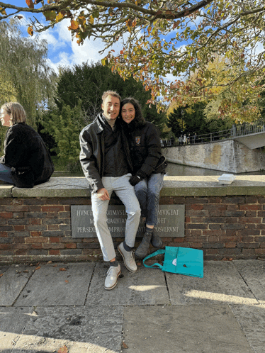 a man and a woman sit on a brick wall with a plaque that says hvct