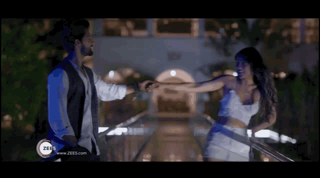 a man and woman are dancing in front of a building that says zees on it