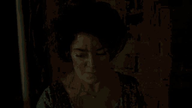 a man and a woman are kissing in a dark room in front of a brick wall .