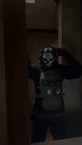 a man in a skull mask is standing in a dark room with his arms outstretched .