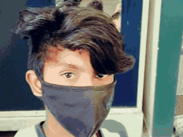 a young boy wearing a face mask with a bun in his hair
