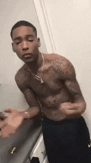 a shirtless man with tattoos on his chest is standing next to a counter .