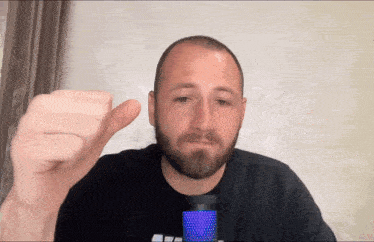 a man with a beard is giving the thumbs down sign