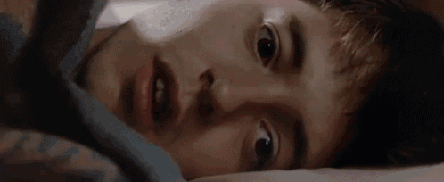 a close up of a young man laying on a bed .