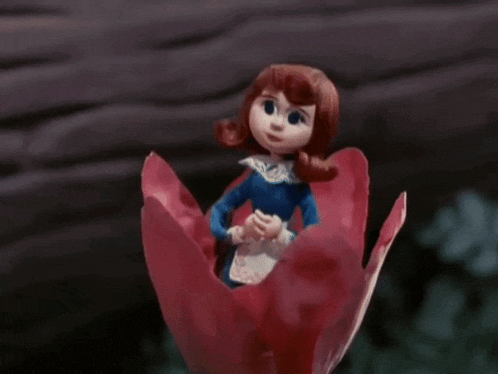 a doll is sitting on a red flower with her eyes closed