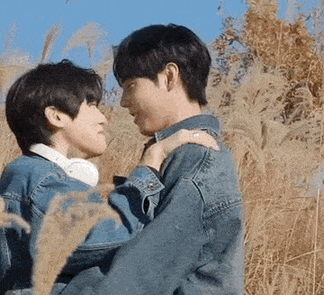 two men are hugging each other in a field of tall grass .