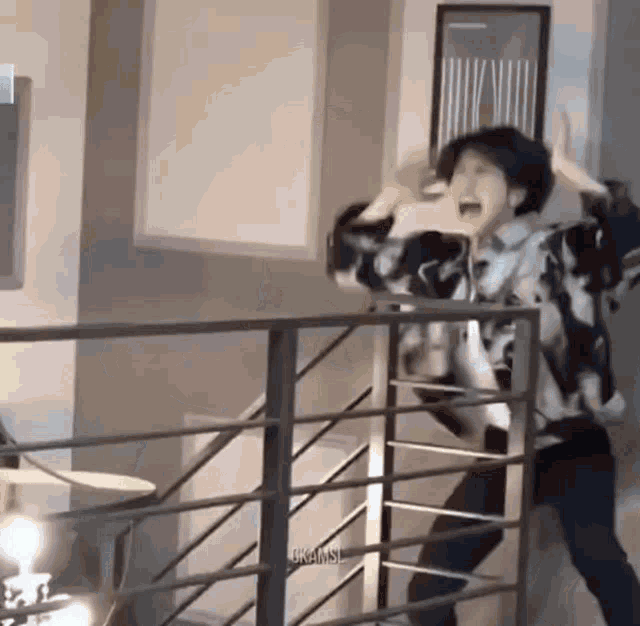 a man is standing on a balcony with his hands in the air and screaming .