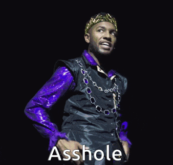 a man wearing a purple shirt and a black vest says " asshole "