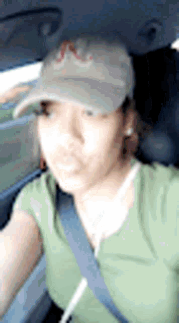 a woman wearing a hat and a seat belt is sitting in the back seat of a car .