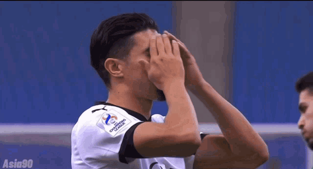 a soccer player covering his face with his hands while wearing a jersey that says champions league on it