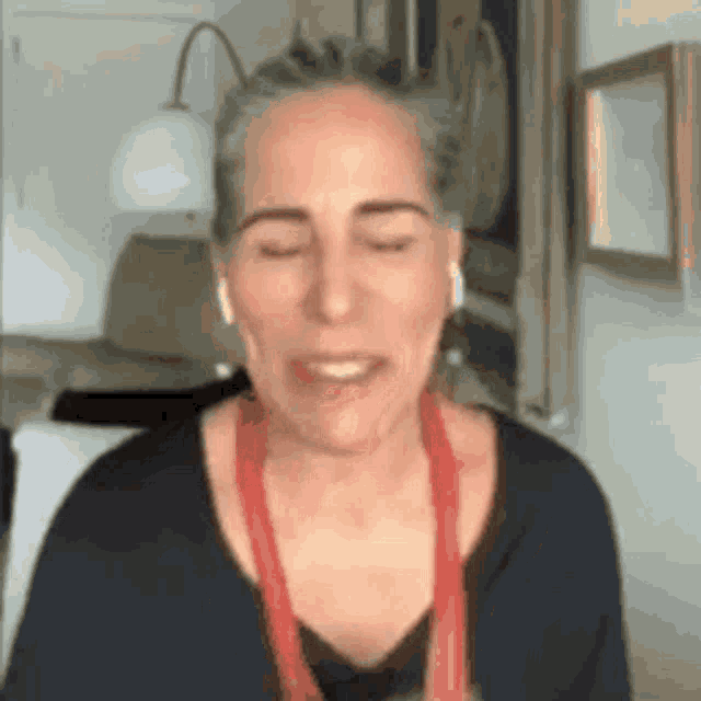a woman is wearing headphones and a red necklace while talking on a video call .