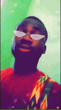 a man wearing sunglasses and a colorful shirt looks down