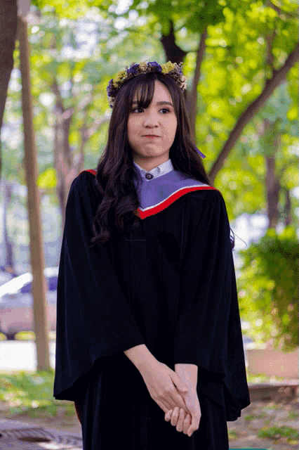 a woman wearing a graduation cap and gown with a flower crown on her head