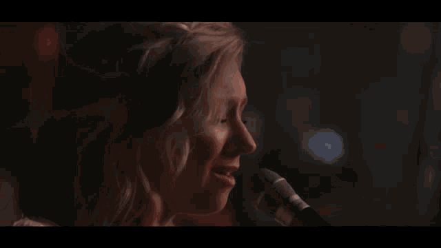 a woman sings into a microphone in front of a crowd of people