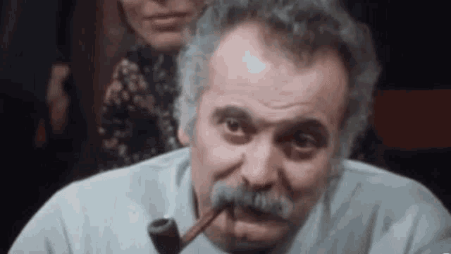 a man with a mustache is smoking a pipe in a bar .
