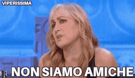 a woman is sitting in front of a blue background and says non siamo amiche .