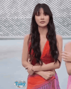 a woman in a red top and purple skirt is standing in front of a sign that says tuky