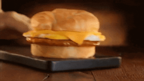 a breakfast sandwich on a croissant on a cutting board