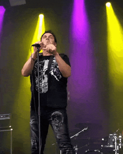 a man singing into a microphone while wearing a black shirt that says tiger king