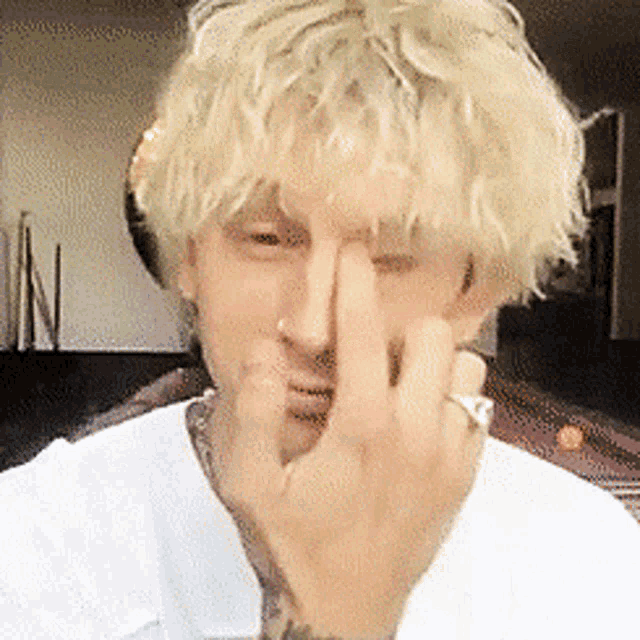 a man with blonde hair is making a face with his finger