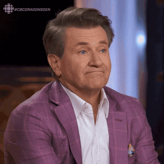 a man wearing a purple suit and a white shirt is making a face