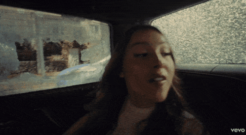 a woman is sitting in a car with the word vevo on the bottom