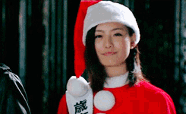 a woman is wearing a santa hat and holding a sign with chinese characters