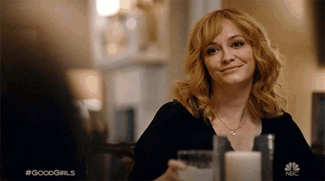 a woman is sitting at a table with a glass of milk and a candle in front of her and the words good girls on the bottom