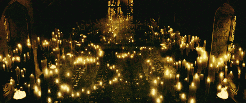 candles are lit up in a dark room with a stained glass window