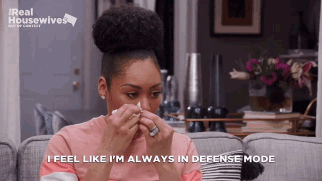 a woman sitting on a couch with the words i feel like i 'm always in defense mode behind her