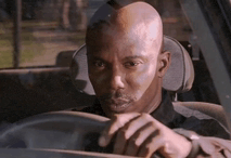 a man is sitting in the driver 's seat of a car and looking out the window .