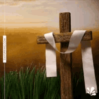 a wooden cross with a white ribbon around it in a field