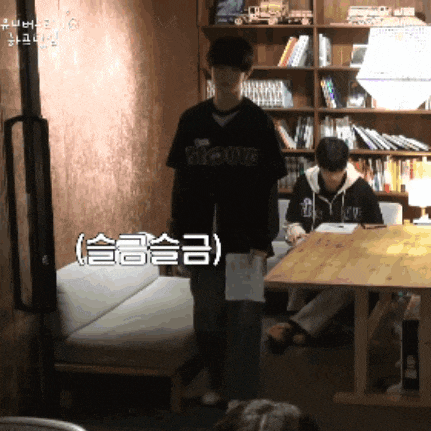 a man wearing a shirt that says hong stands in front of a table