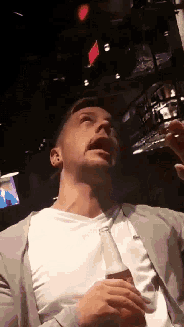 a man in a white shirt is holding a bottle of soda in his hand