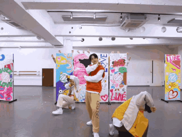 a group of young men are dancing in front of a wall that says love