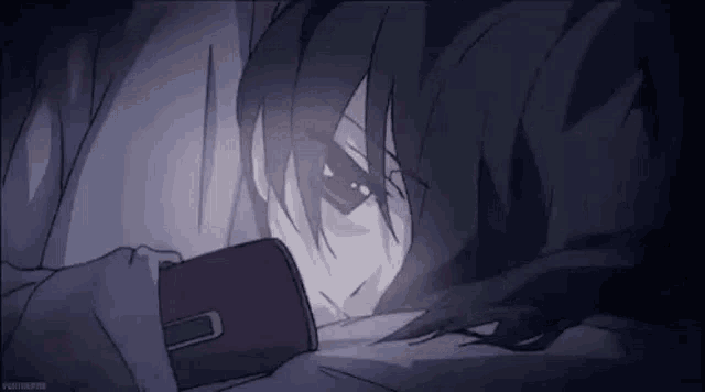a person is laying in bed looking at a cell phone .