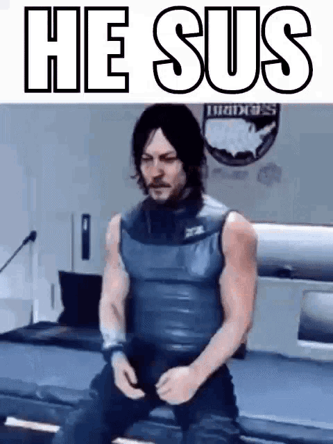 a man in a tank top is sitting on a bed with the words `` he sus '' written above him .