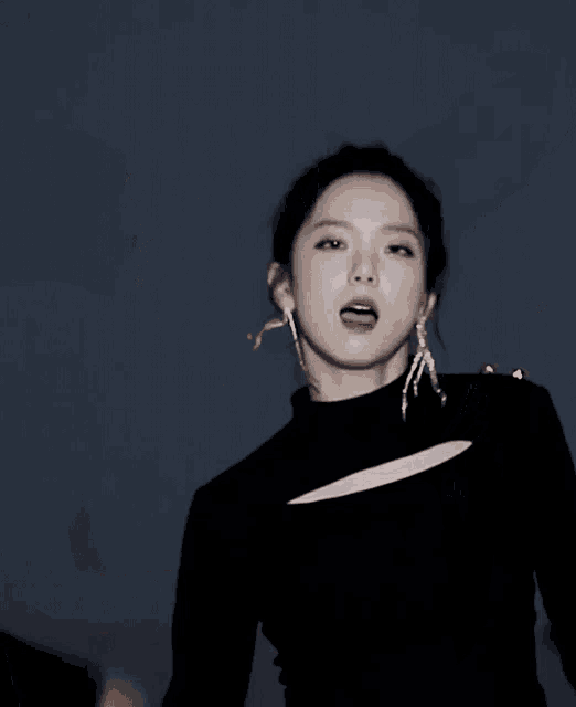 a blurry picture of a woman wearing earrings and a black top .
