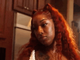 a woman with red hair and cat ears is standing in a kitchen .