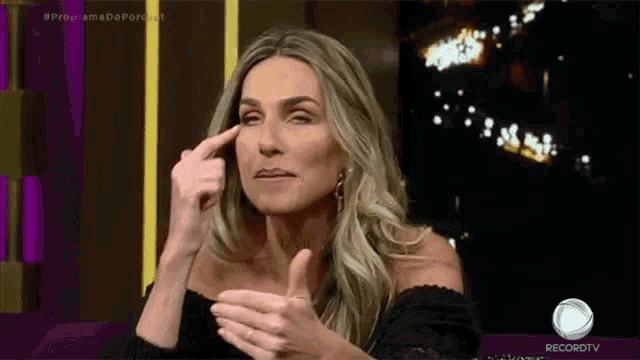 a woman is pointing at her forehead while making a face .