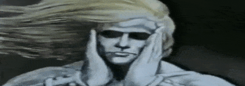 a statue of a man with blonde hair is covering his ears with his hands .
