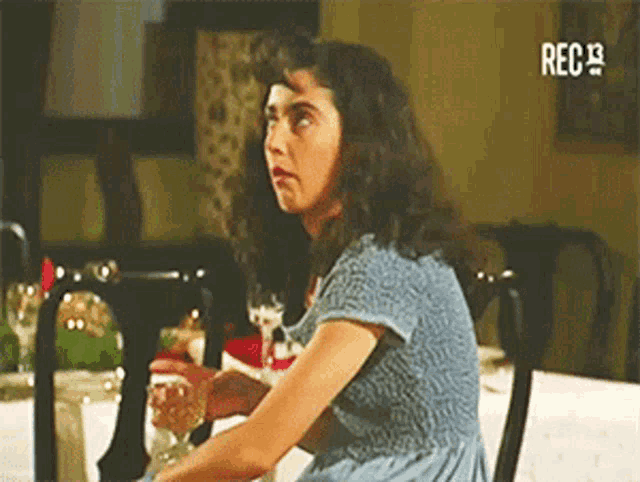 a woman in a blue dress is sitting at a table with a rec9 logo on the bottom right