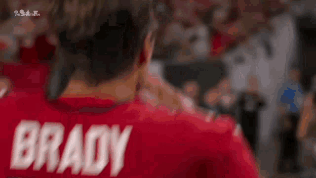 a man wearing a red jersey with the name brady on the back