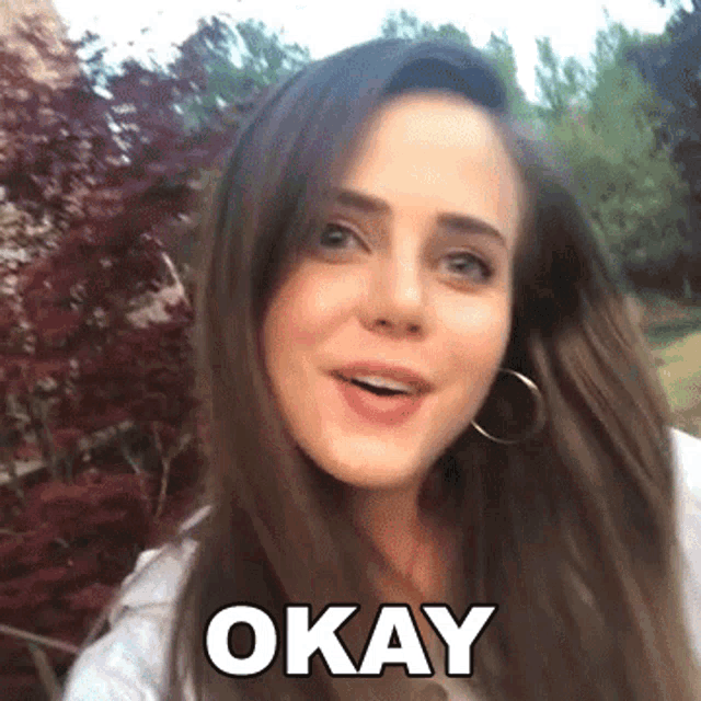 a woman with long hair is smiling and saying okay .