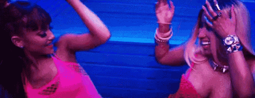 two women are dancing together in front of a blue wall in a club .