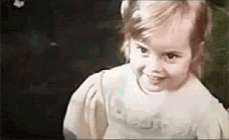 a little girl is smiling and looking at the camera in a blurry photo .