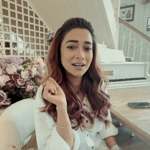 a woman sitting in front of a white piano