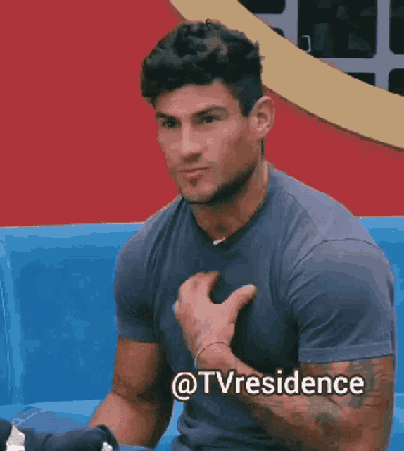 a man is sitting on a blue couch and has the hashtag @tvresidence on his chest