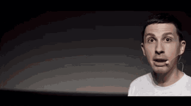 a man with a microphone in his ear is making a funny face and sticking his tongue out .